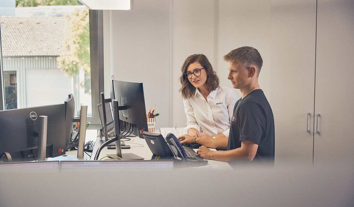 Mitarbeitende arbeiten gemeinsam an einem Arbeitsplatz.